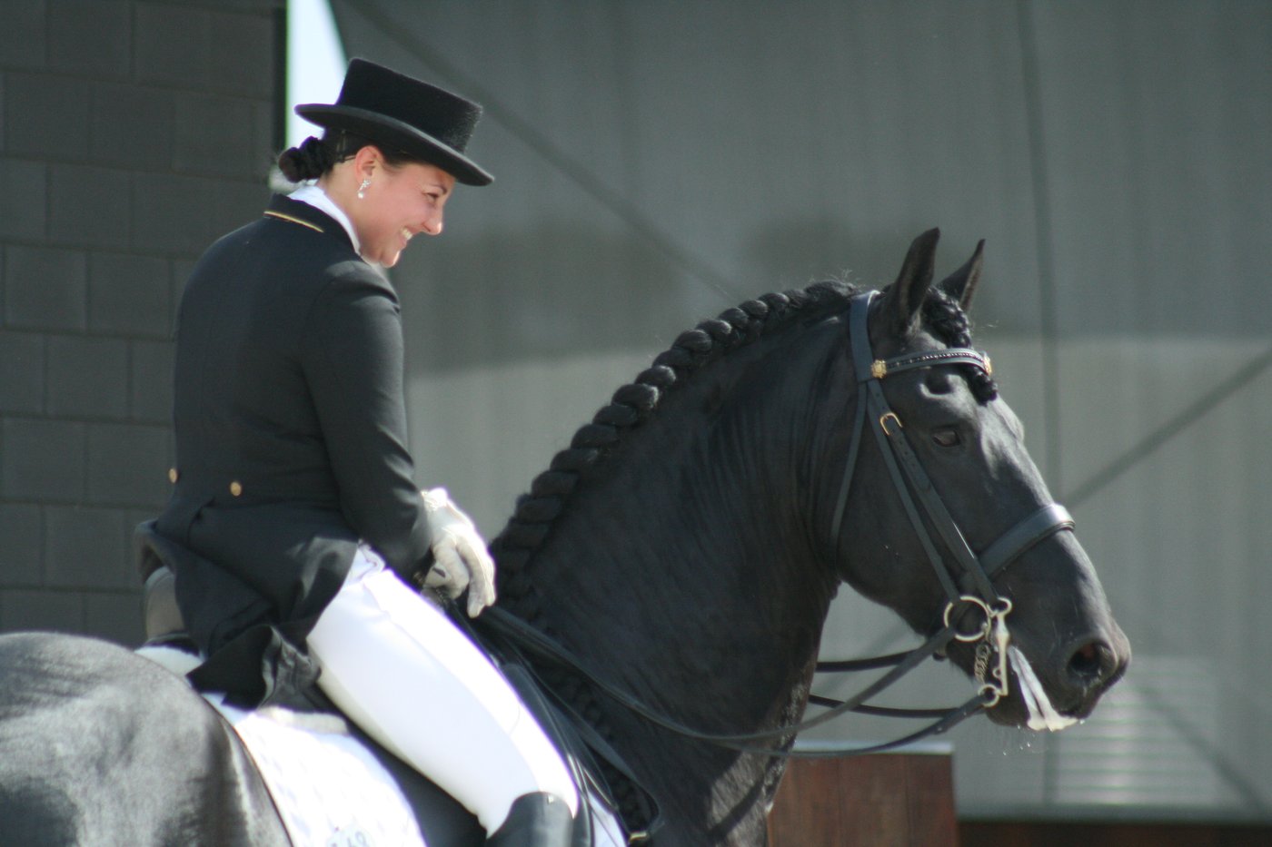 Natasha Althoff riding her Friesian stallion at Grand Prix in top hat and tails